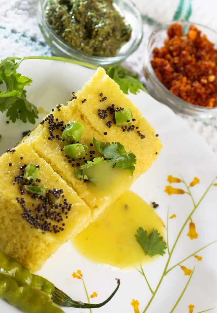 khaman is a food common in the Gujarat , made from soaked and freshly ground chana dal .The final touch to the soft and fluffy khaman is added with a garnishing of sesame seeds, mustard seeds, coriander leaves. It is a variant of Dhokla and has a lighter colour.
